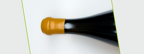 Wassen capsules op wijnflessen.