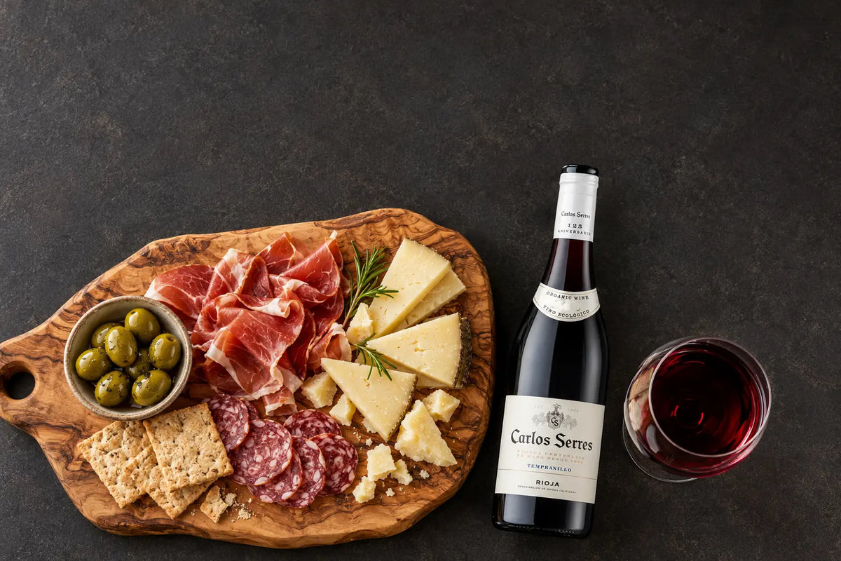 Wijnen Borrelplank met kaas en tapas naast een fles wijn en een wijnglas, van bovenaf gezienbij de borrelplank